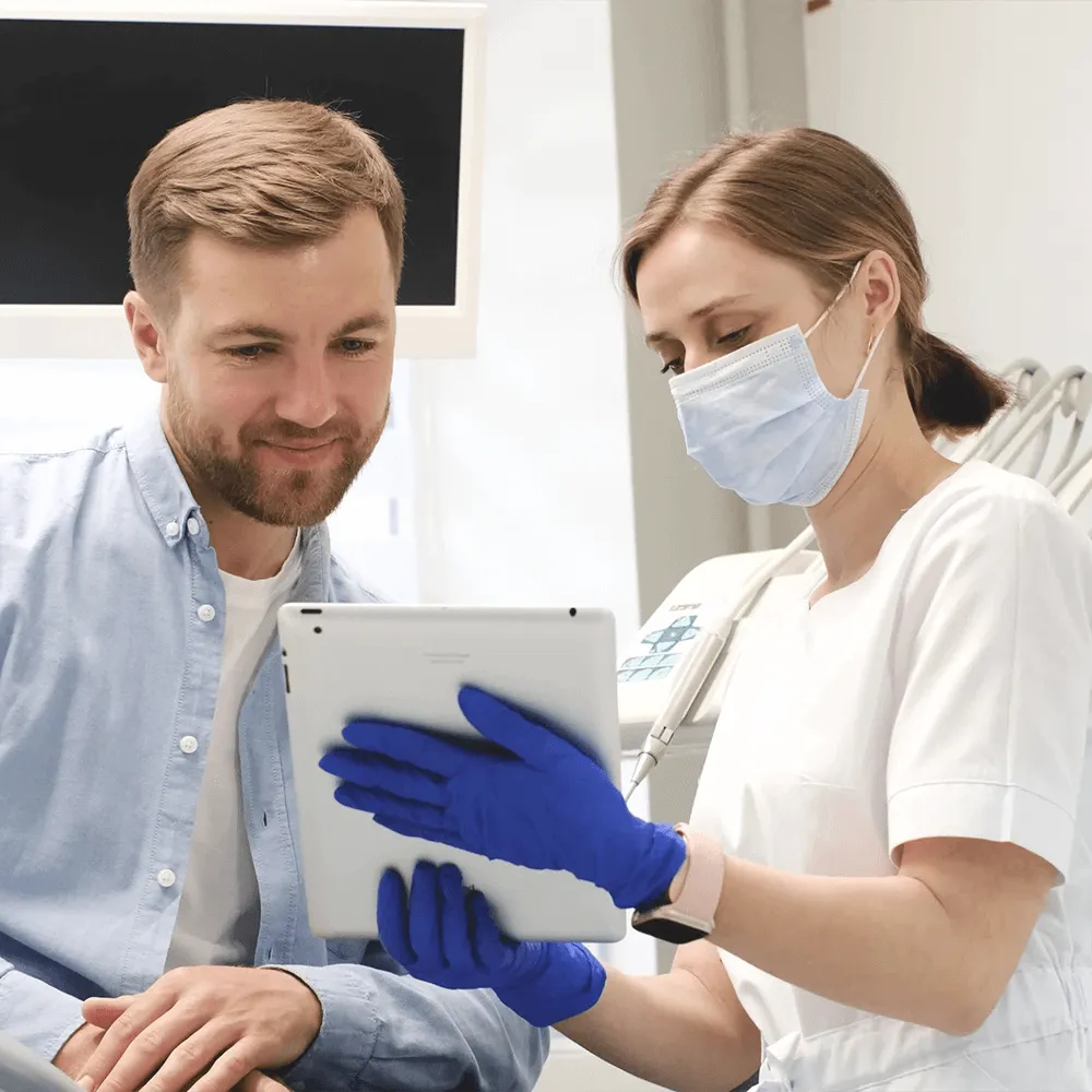 Dentist showing patient dental X-rays on tablet.