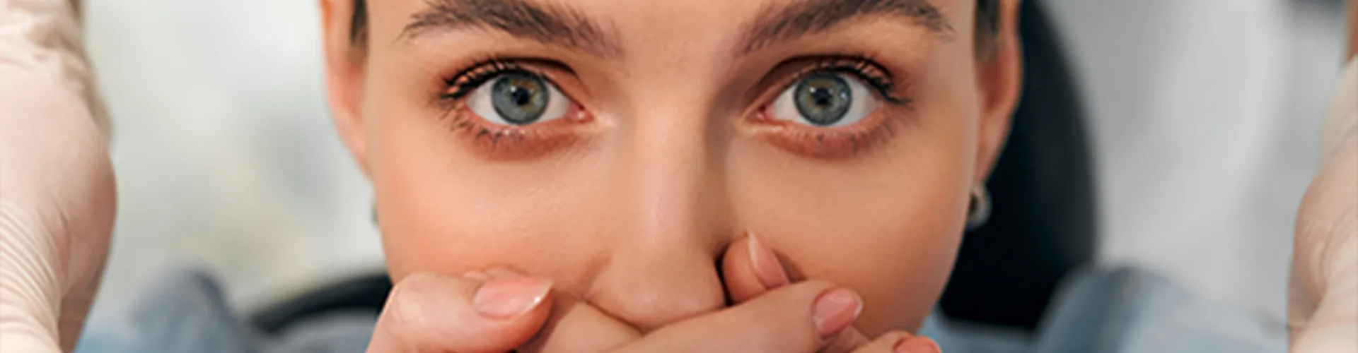 Woman covering her mouth with both hands.