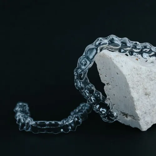 Two clear aligners on a black surface with a white rock.