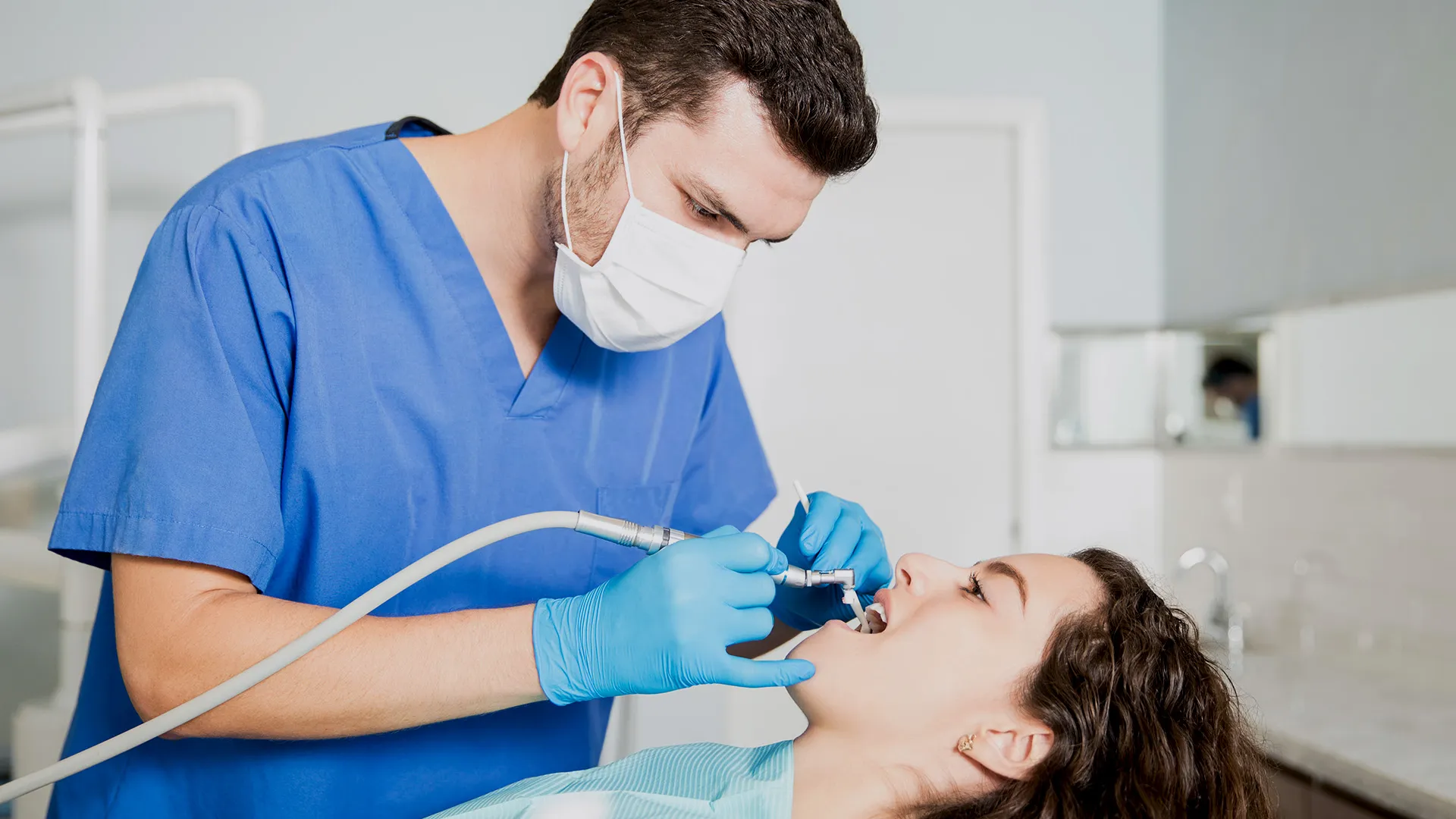 Dentist cleaning patient’s teeth with tools.