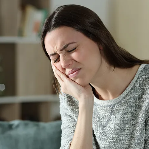 woman holding her jaw in pain