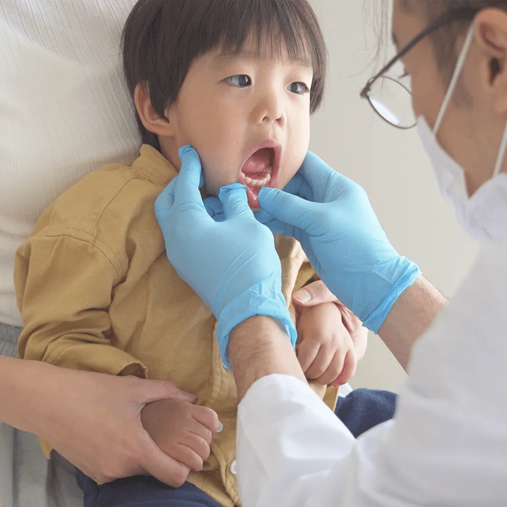 Pediatrician examining a toddler's teeth during a checkup.