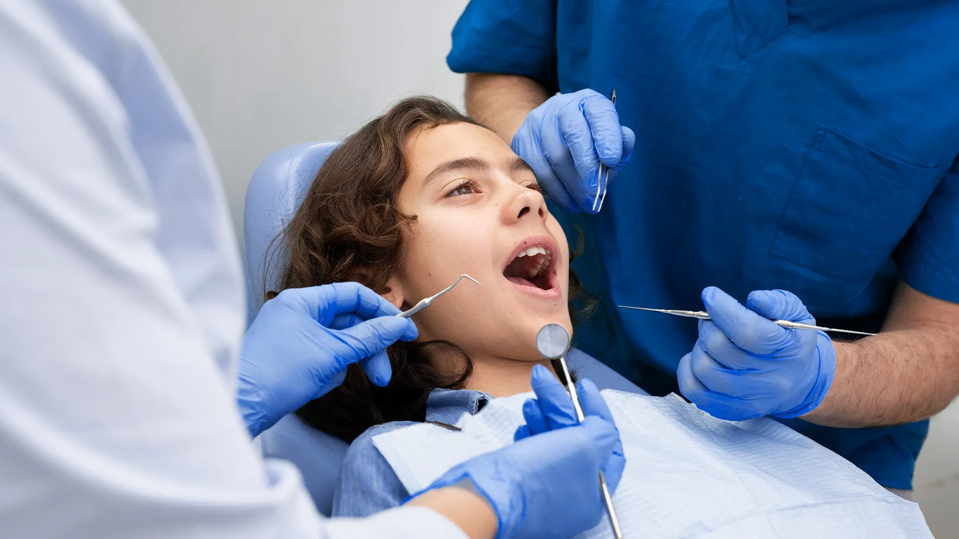 Child receiving dental examination with instruments.