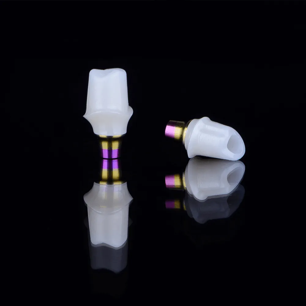 White dental abutments with purple-gold bases on black background.