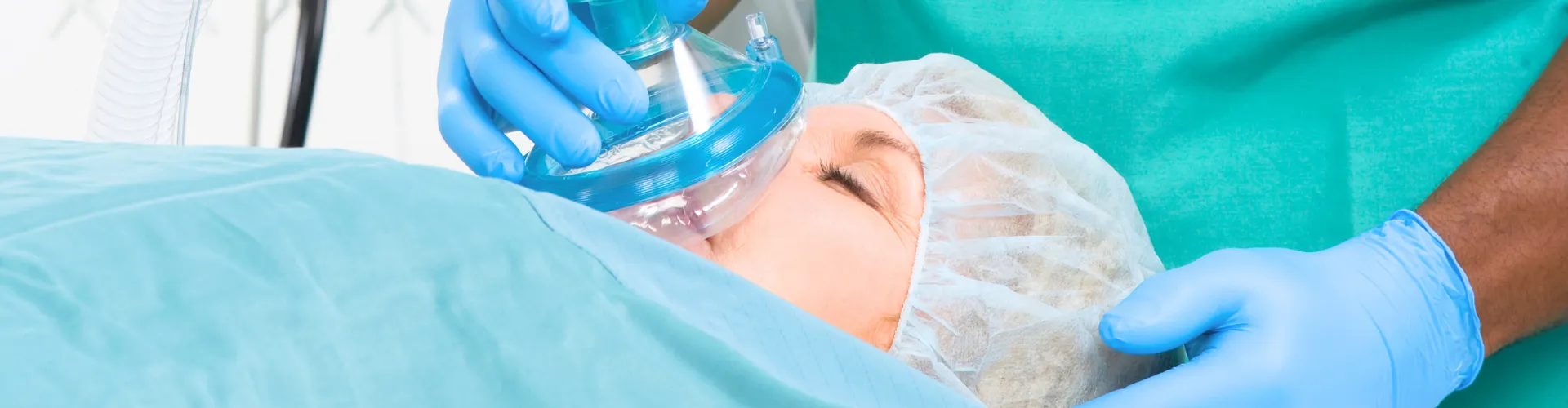 Gloved hands placing breathing mask over woman's face.