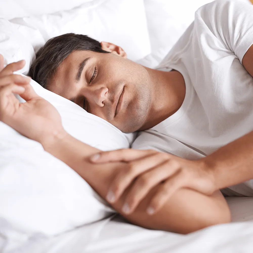Man sleeping peacefully in bed, enjoying restful sleep.