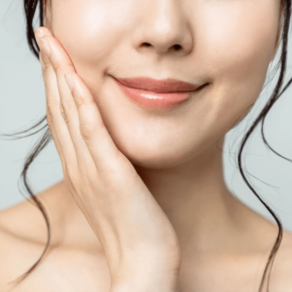 Close-up of a woman's face, showcasing healthy, glowing skin and a subtle smile.