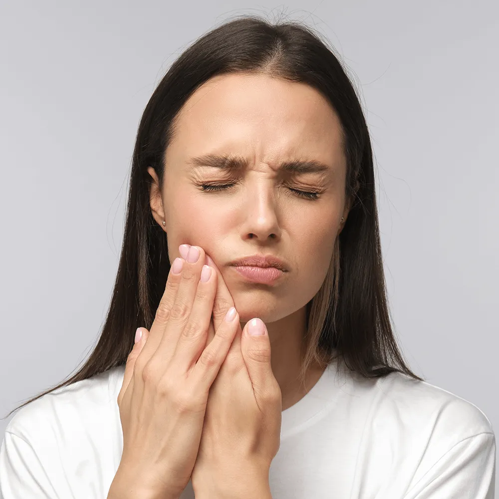 Woman with hand on jaw experiencing toothache pain.