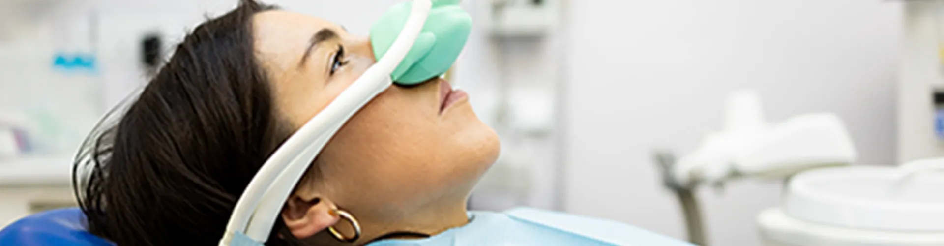 Child in dental chair with breathing mask over nose.