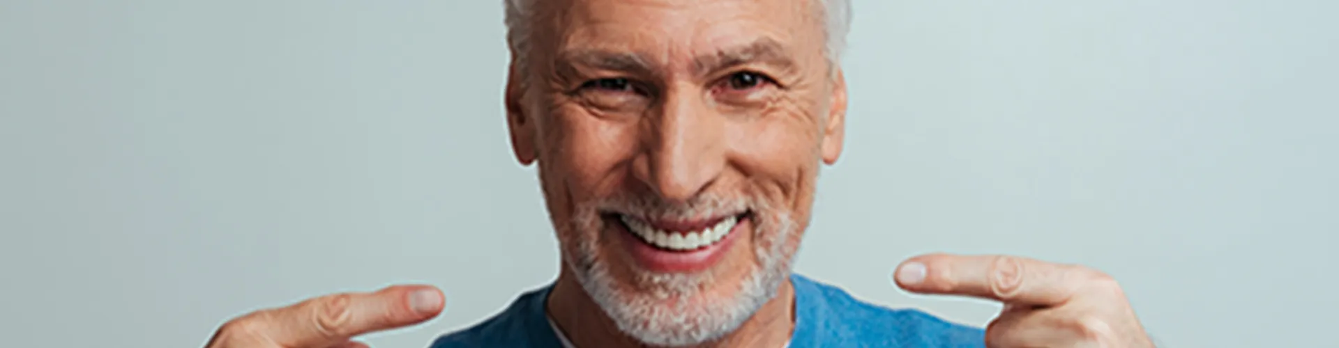 Man pointing at his smile with both hands.