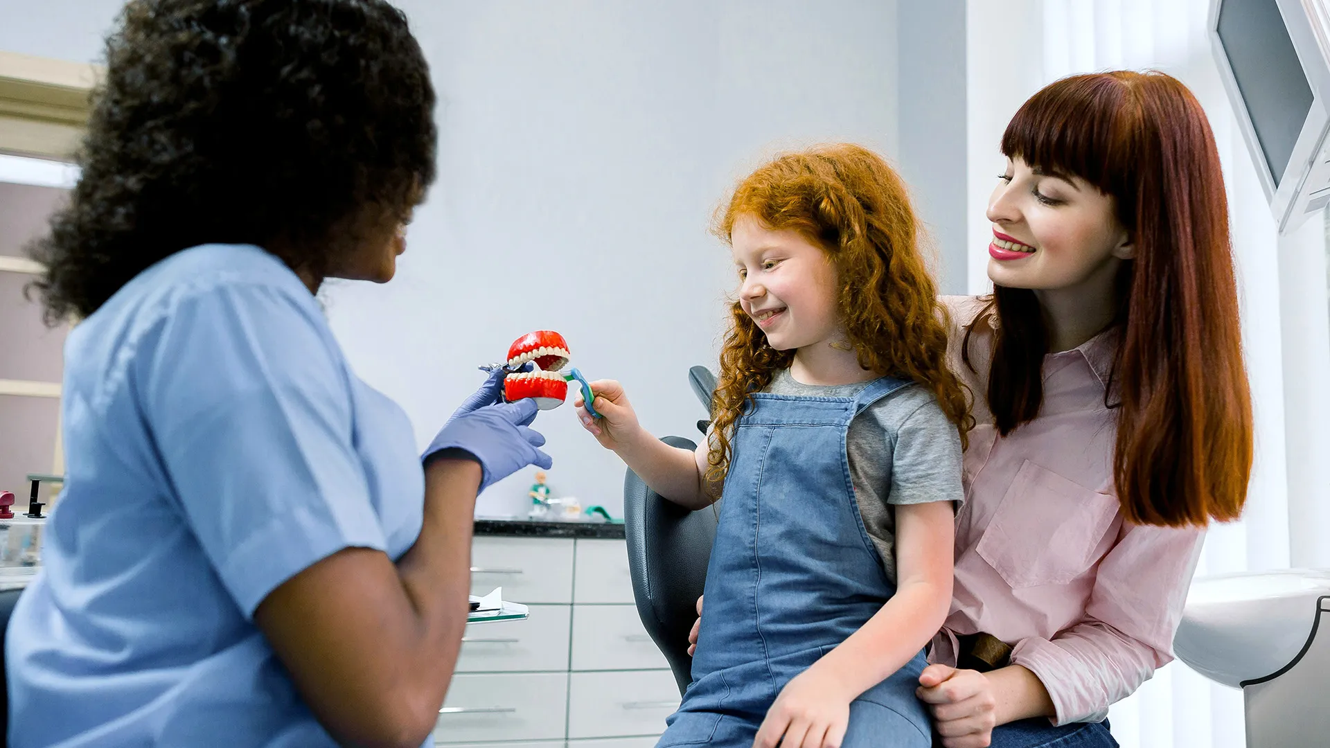 Child learning brushing technique with dentist.