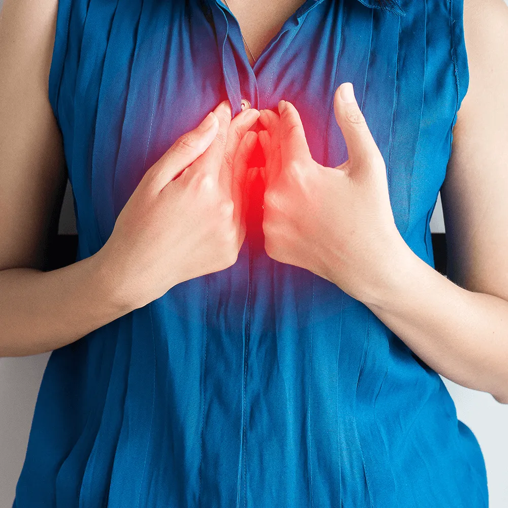 Woman holding chest, experiencing chest pain.  Heart attack symptoms.