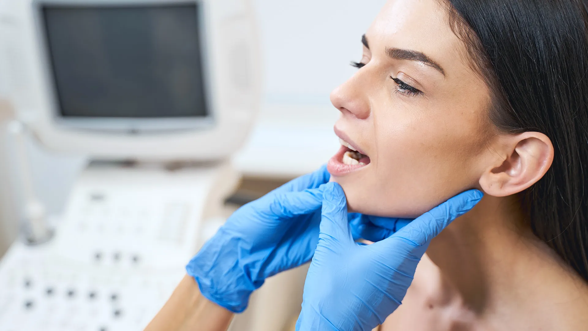 Dentist examining woman’s jaw for TMJ.