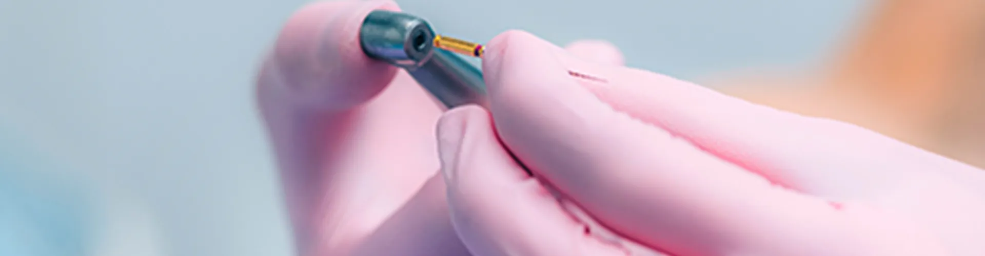 Gloved hands holding dental tools.