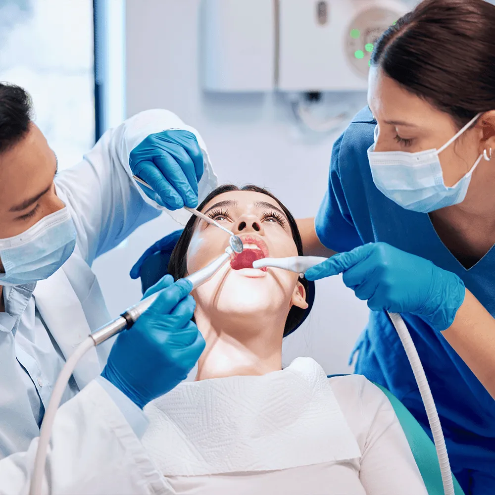 Dental hygienists performing a teeth cleaning on a patient.