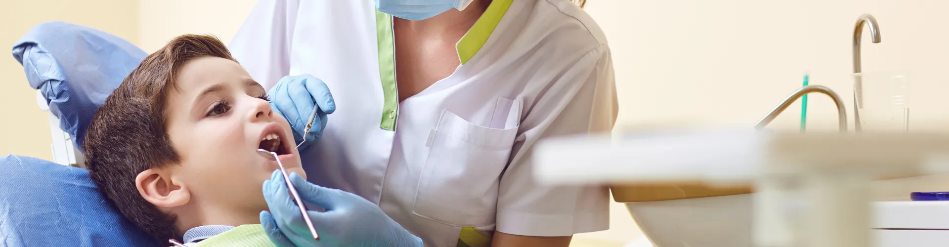 Dentist using dental tools in child's mouth.
