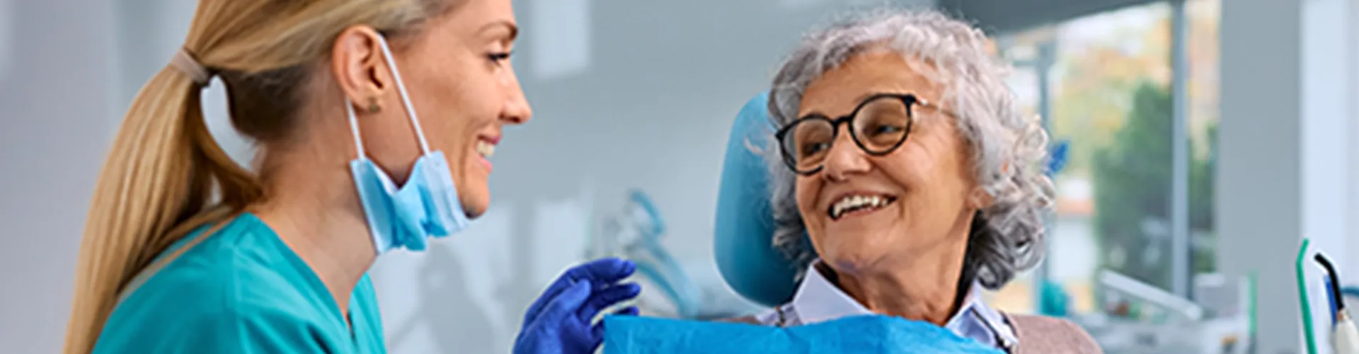 Female denstist speaking with older female patient.