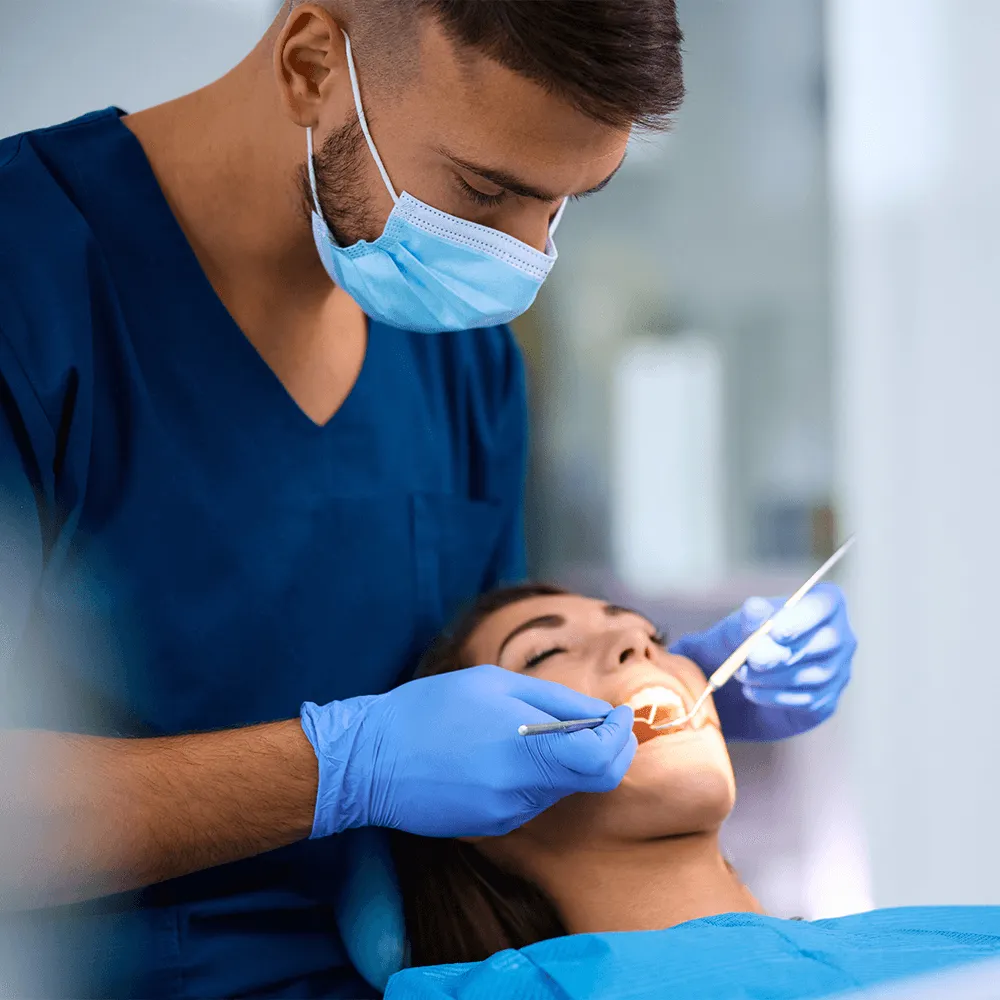 Dentist examining patient's teeth with dental tools.