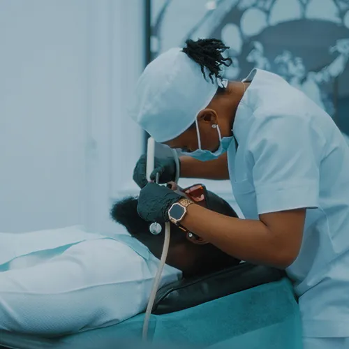 Dentist repairing cavity in mouth of patient laying in dental chair.