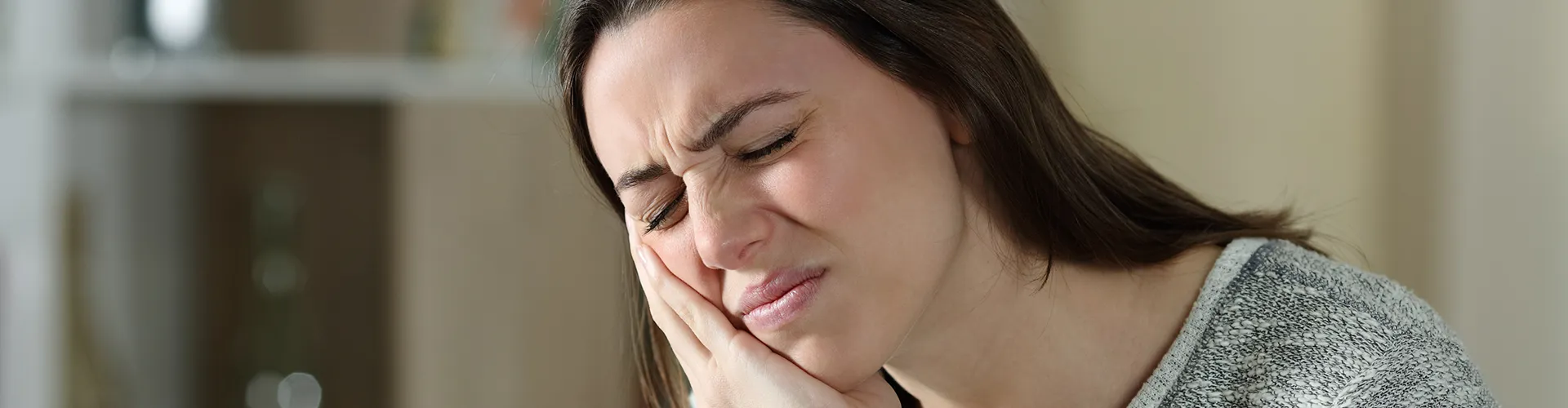 Woman holding her jaw in pain.