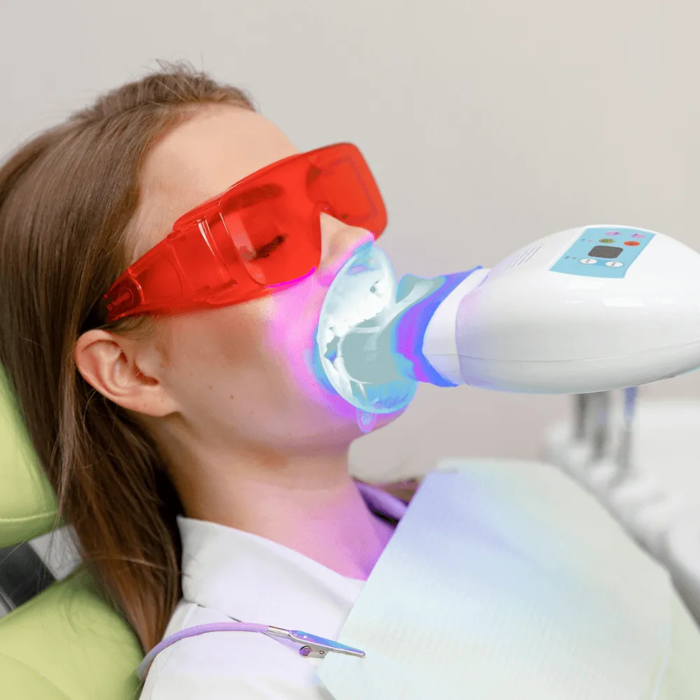 Woman receiving professional teeth whitening treatment with LED light.
