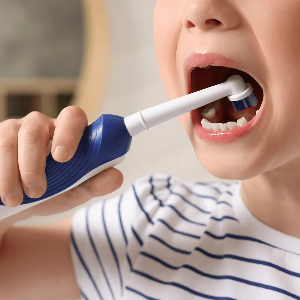Child brushing teeth with electric toothbrush.