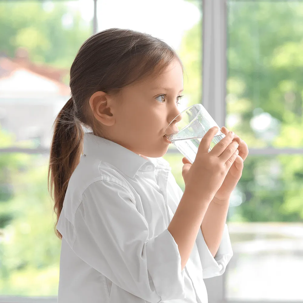Young girl drinking water from a glass.