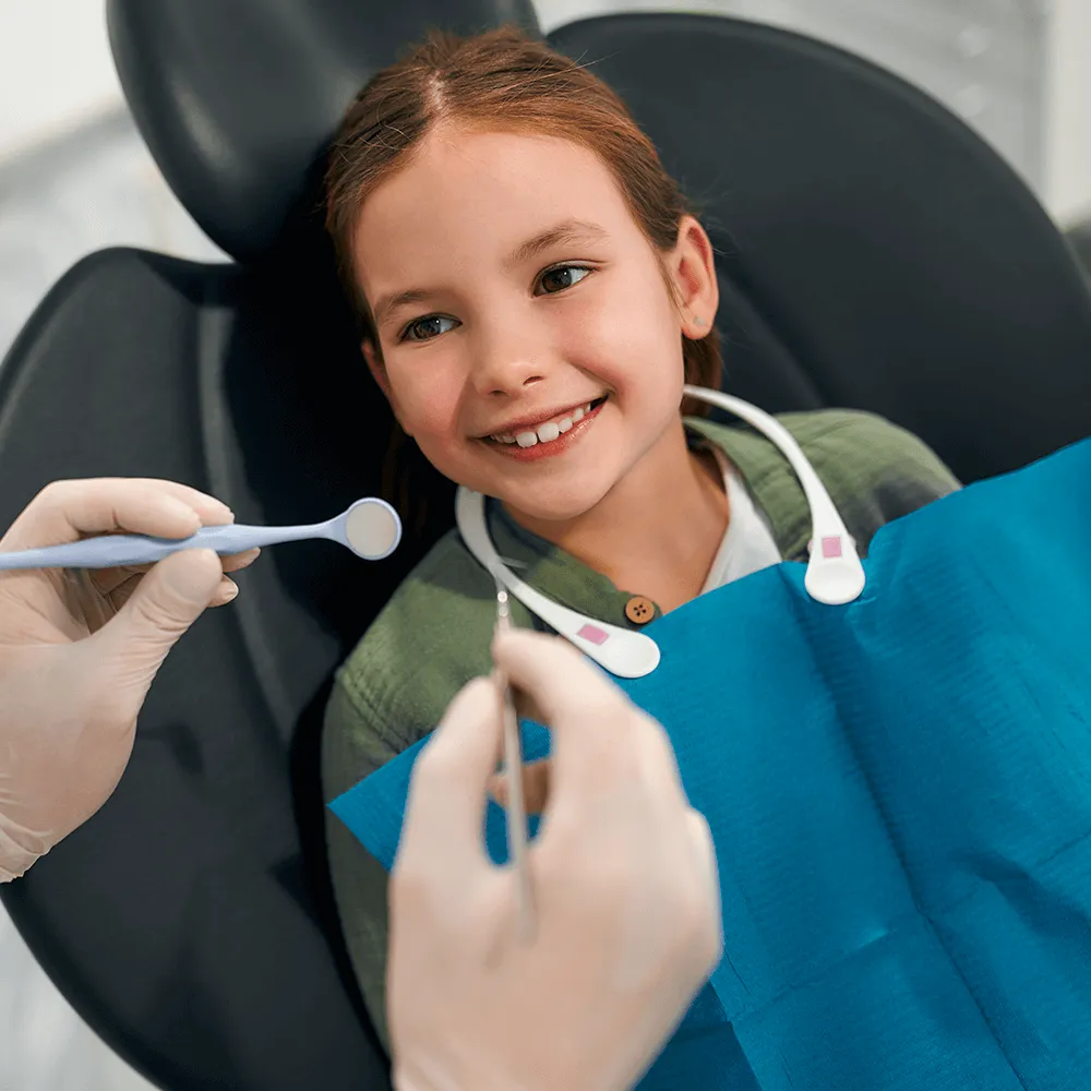 Happy girl at dentist appointment, smiling during checkup.