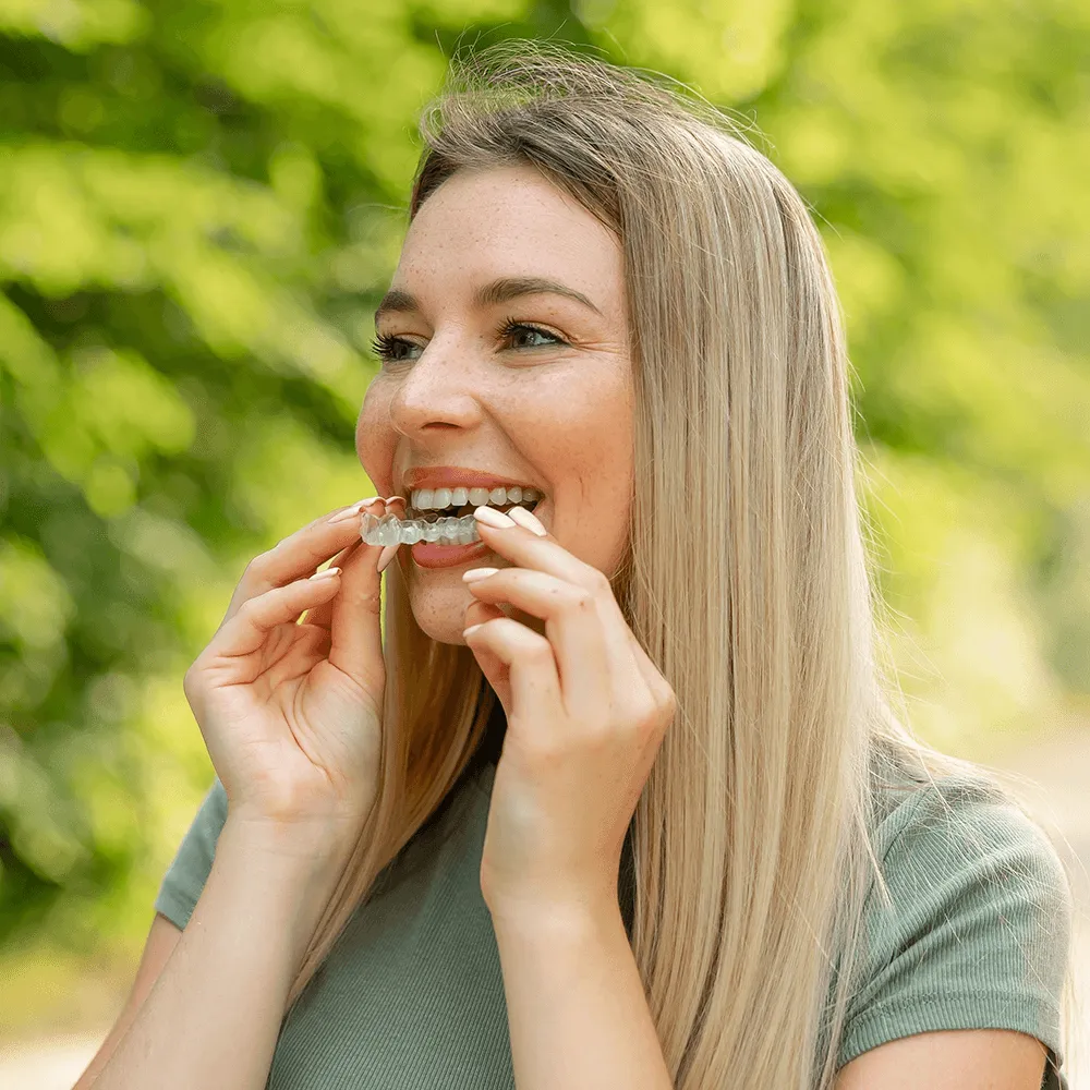 Woman putting in clear aligner for teeth straightening.
